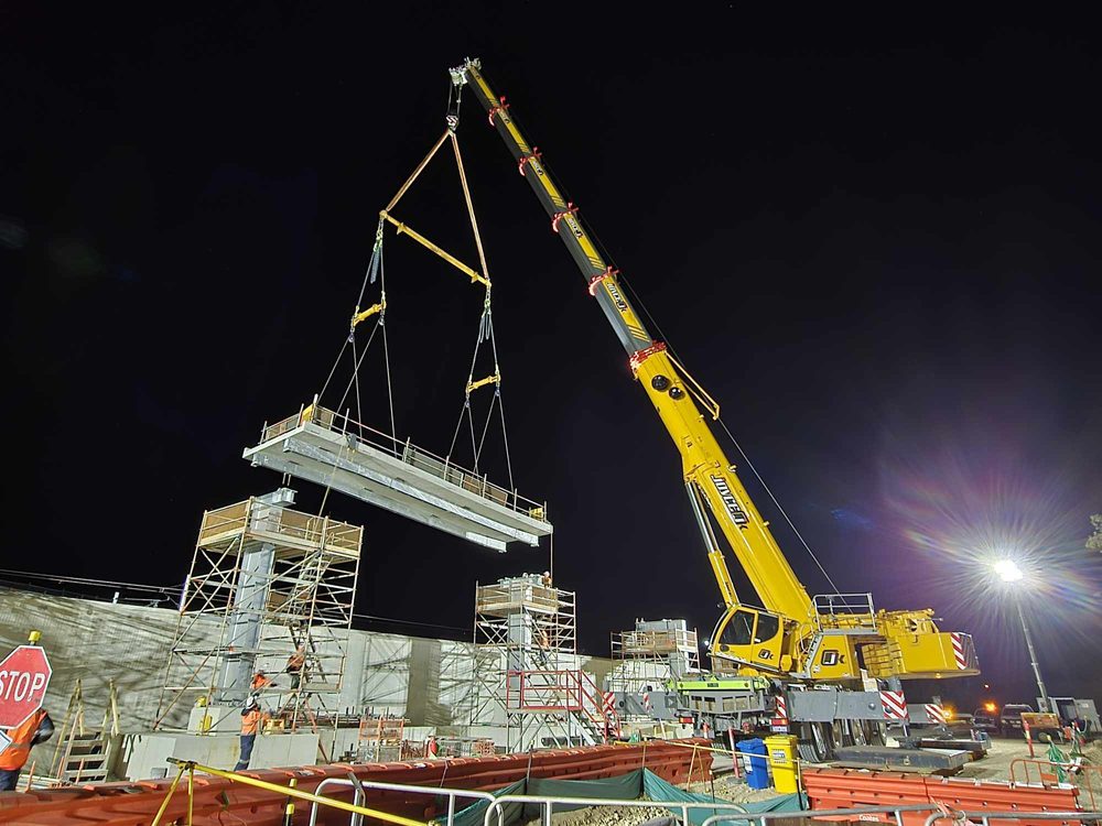 Joyce Krane crane lifting a beam on a construction site at night